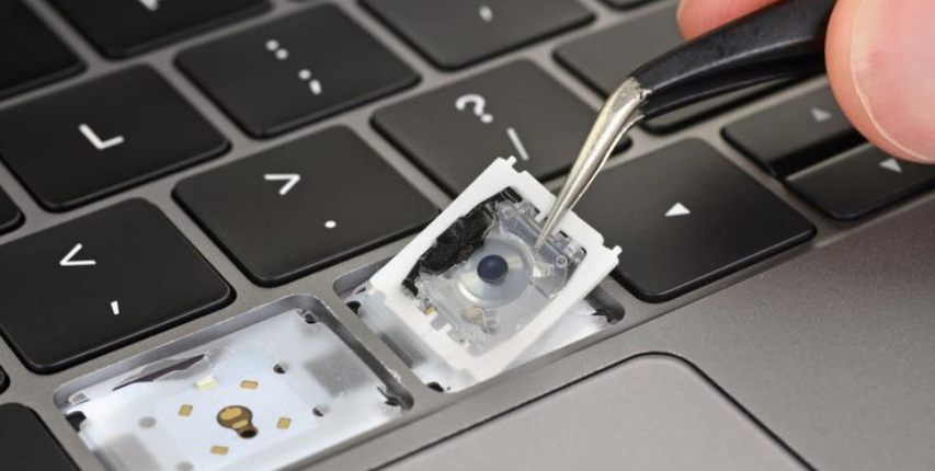 Technician repairing a laptop keyboard with professional tools